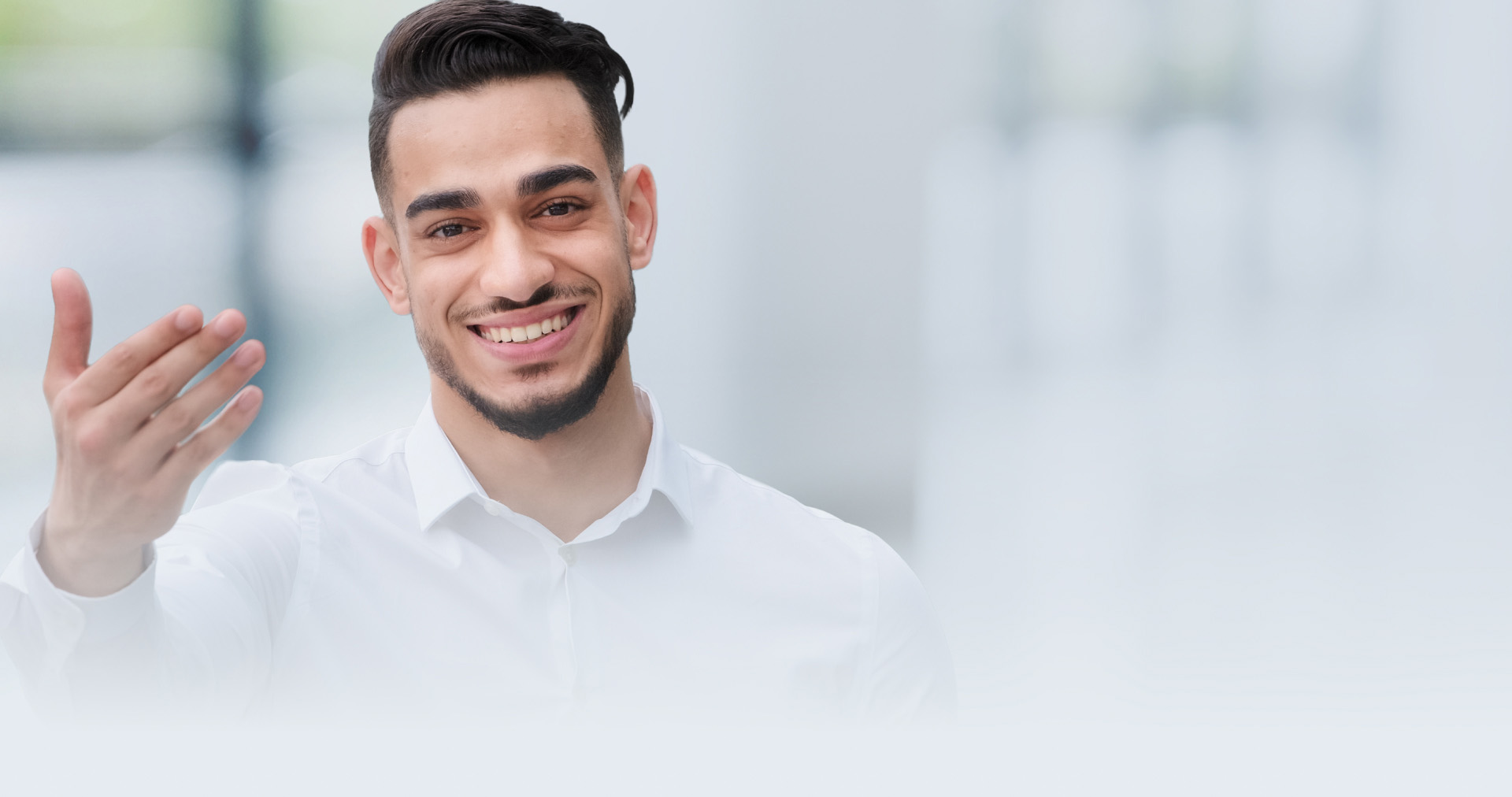 Latinx man in a white collared shirt signing "welcome" in ASL.