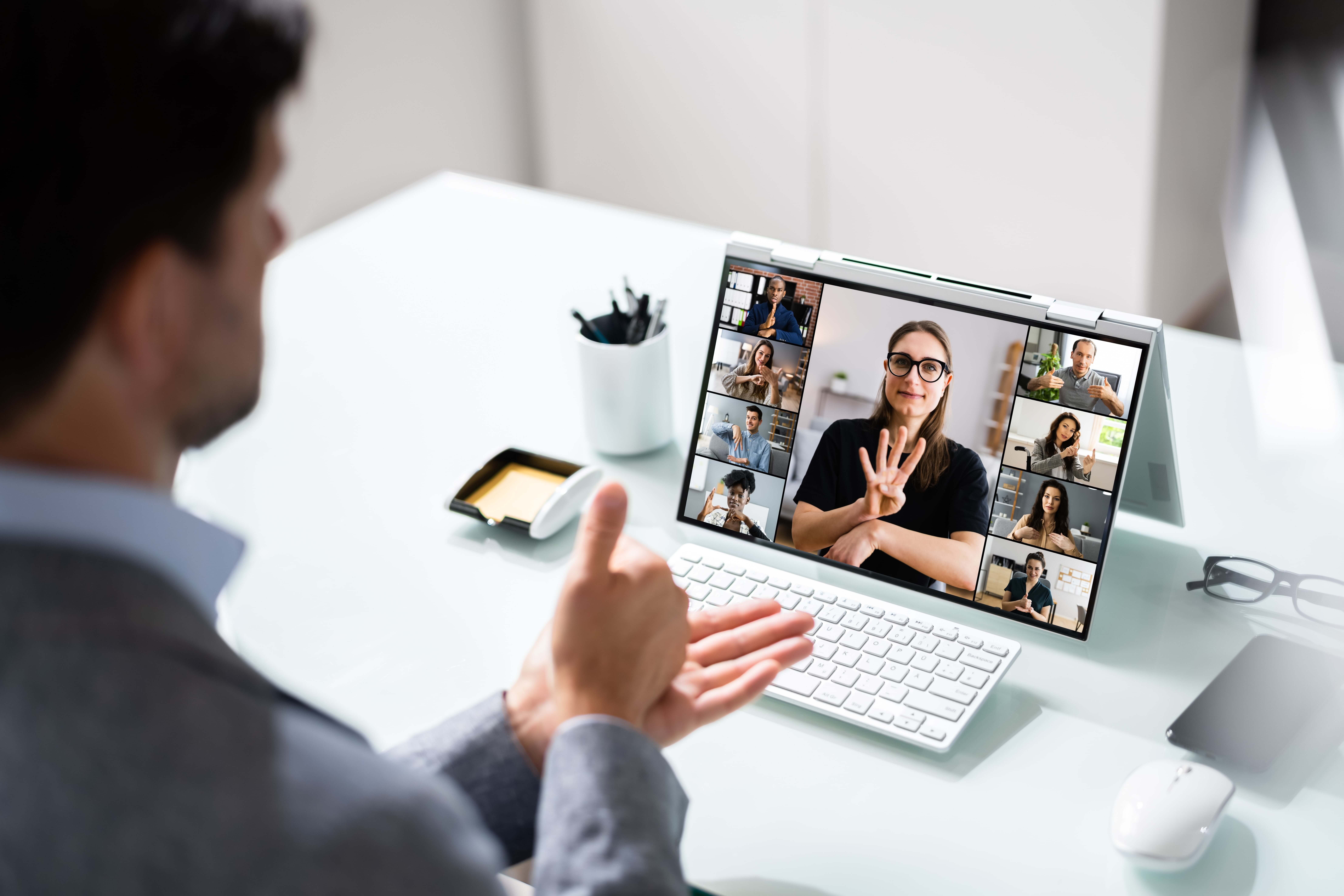 Man in front of a laptop using sign language on a video call.
